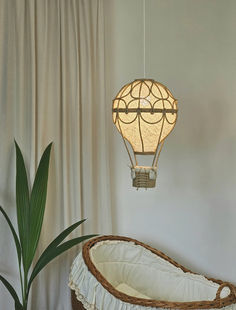 a lamp hanging from the ceiling over a crib next to a potted plant