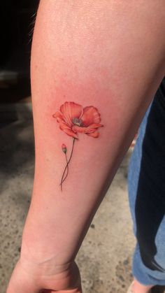 a woman's arm with a red flower tattoo on the left side of her leg