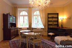 a living room filled with furniture and a chandelier hanging from the ceiling next to a window