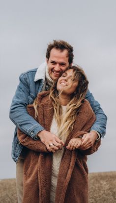 a man and woman hugging each other in the middle of a field