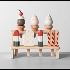 three ice cream cones sitting on top of a wooden bench next to other desserts