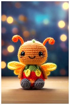 a small crocheted stuffed animal sitting on top of a wooden table with lights in the background