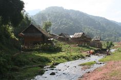 a river running through a lush green hillside covered in grass next to houses and trees