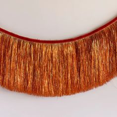 an orange and red fringe is hanging on a wall