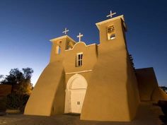 an adobe church with two crosses on the roof