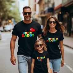 the man and woman are walking down the street with their child wearing matching t - shirts