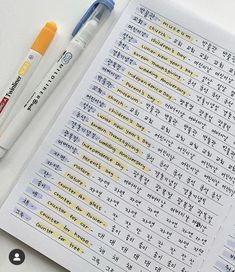 two pens sitting on top of an open notebook next to some writing paper with chinese characters