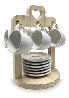 a stack of white plates and cups on a wooden stand with a heart - shaped hanger