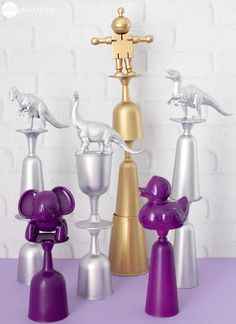 three different colored vases and one gold figurine on a purple countertop