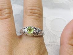 Natural Peridot Ring Etched Wedding Design#160 Made To Order Here we have a Victorian/Edwardian reproduction ring in sterling silver with a stunning natural peridot gemstone. This full cut round peridot gem is 6mm in diameter. The inside of the band is marked 925 for sterling. Notice the beautiful floral design of the silver filigree setting and band. This is a lovely rendition of an Antique filigree ring; and it is ready to wear. A gift ring box is included and all rings are shipped in the box Green Engraved Wedding Rings, Lime Green Round Jewelry For Wedding, Lime Green Wedding Rings With Accent Stones, Lime Green Wedding Rings, Ornate Green Wedding Ring, Vintage Peridot Rings For Wedding, Antique Filigree, Sterling Silver Filigree, Peridot Ring