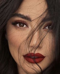 a woman's face with red lipstick on her lips and long dark black hair