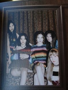 a group of young women sitting next to each other in front of a wooden frame