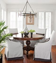 a dining room table with white chairs and a chandelier hanging from the ceiling