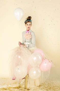 a woman sitting on top of a chair with balloons