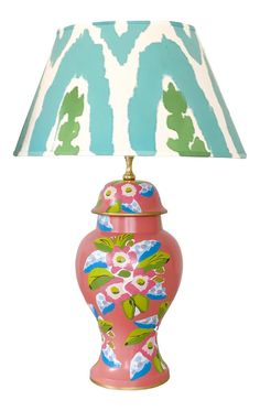 a pink and blue vase lamp with a white shade on it's side,