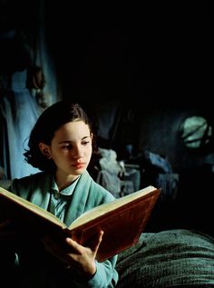 a woman sitting on a bed reading a book