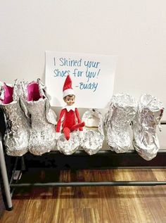 an elf is sitting on top of some tin foil wrapped shoes and holding a sign that says, shred your shoes for you buddy