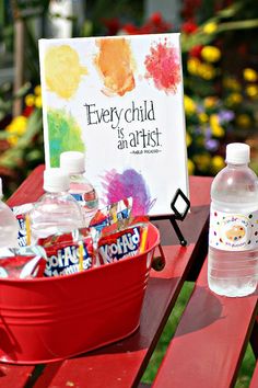 a red bucket filled with lots of water sitting on top of a table next to a sign