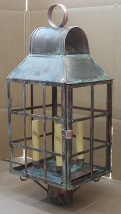 a metal lantern with candles in it sitting on the floor next to a cardboard box