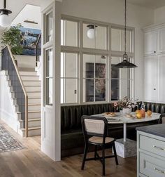 a kitchen and dining area with white walls, wood flooring and black leather couches