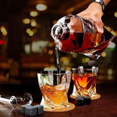 a person pours whiskey into glasses with ice cubes