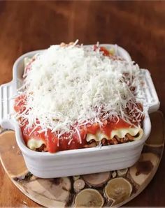 a casserole dish with cheese and sauce on it sitting on a wooden table