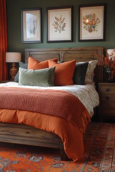 a bed with orange sheets and pillows in a bedroom next to two pictures on the wall