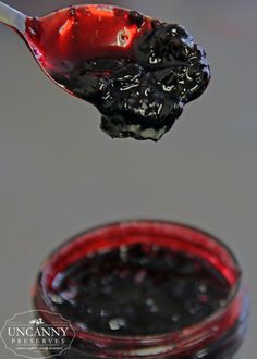 a spoon full of black liquid with a red container in the background