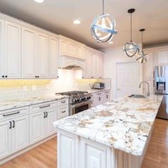 a large kitchen with white cabinets and marble counter tops