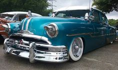 an old blue car parked in a parking lot