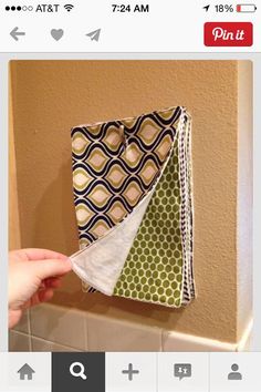 a person is holding three pieces of fabric in front of a tiled wall