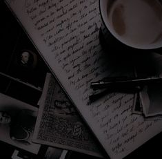 a coffee cup and pen sitting on top of an old paper with writing in it