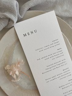 a plate with a menu on it next to a napkin and some flowers in the middle