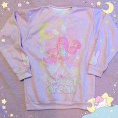 Re-Release of the popular design, now made with heavier fabric and a softer pastel pink shade.If you love soft pastel shades, comfy sweaters and bunnies, this is for you!A cute chibi bunny girl, dreamily floating on some soft clouds with the words 'sweet dream' below her.Sleeve illustrations include pastel yellow stars and cute white bunnies. Back of the sweater reads 'good night'86% Polyester, 14% CottonShips from the USA. Pink Crew Neck Top With Bunny Design, Cute Cartoon Print Sleep Tops, Cute Sleep Tops With Cartoon Print, Cute Pink Top With Bunny Print, Cute Pink Tops With Bunny Print, Cute Pink Bunny Print Tops, Cute Pastel Tops, Cute Chibi Bunny, Chibi Bunny