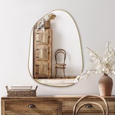 a mirror sitting on top of a dresser next to a vase