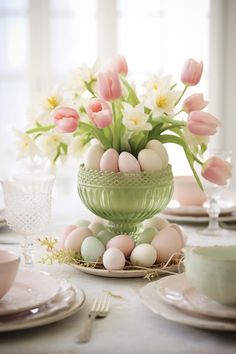 a green bowl filled with eggs sitting on top of a table next to plates and cups