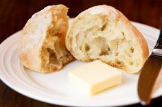 a piece of bread sitting on top of a white plate next to a butter knife