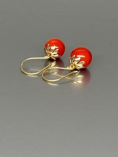 Gorgeous polished vibrant red coral globe earrings. The 12mm coral globes attached to beautiful 14K gold-filled flower caps as they dangle from the 14k gold-filled ear wires. The red globes are perfectly weighted while still being very comfortable to wear A truly gorgeous pair of earrings. *AAA coral spheres *Ball size (diameter): 12mm *Metal: 14K gold-filled *Earrings drop length: 31mm / 1.2 inch Solid gold, silver, and gemstones are also my materials of choice, I love working with these beauti Elegant Red Coral Earrings, Elegant Red Coral Drop Earrings, Elegant Coral Colored Red Coral Earrings, Elegant Red Coral Dangle Earrings, Elegant Red Coral Jewelry With Matching Earrings, Globe Earrings, Sphere Earrings, Red Stone Earrings, Ball Earrings