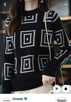 a woman wearing a black sweater and white skirt holding a handbag in front of her face