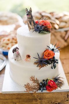 a wedding cake decorated with flowers and a dog figurine