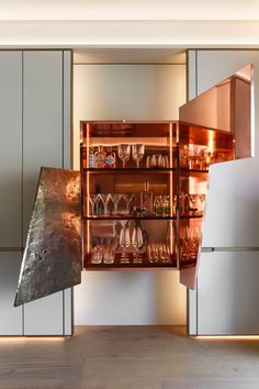 an open cabinet in the middle of a room filled with wine glasses and other items