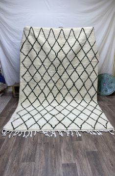 a white and black rug with fringes on the floor in front of a wall