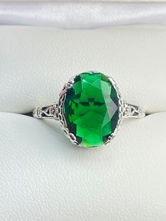 6ct. Simulated Emerald 925 Sterling Silver RingEdward Design#D70 This filigree ring is a reproduction of a sterling silver Edwardian antique with a simulated green emerald gemstone solitaire. This full cut oval gem is 14mm x 10mm. This ring sits 7mm off the finger. The inside of the band is marked 925 for sterling silver. Notice the beautiful leaf and floral design of the silver filigree setting and etched band. This ring is part of our Edward series, which includes bracelets, earring, and pendant necklaces. This is the original Edward design, with a generously cut gemstone that is accented above the filigree. This is a lovely rendition of an antique filigree ring. This amazing design is pure style and grace. You can dress it up or down, it's the perfect statement. Your every movement will Green Elegant Filigree Ring For Formal Occasions, Elegant Green Filigree Ring For Formal Occasions, Green Elegant Formal Filigree Ring, Classic Green Ring With Center Stone, Antique Green Emerald Ring With Prong Setting, Classic Green Rings With Center Stone, Elegant Filigree Emerald Ring For Formal Occasions, Elegant Formal Emerald Ring With Filigree, Elegant Formal Emerald Filigree Ring