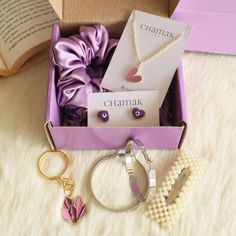 an open box containing jewelry and pearls on a white furnishing with a purple ribbon