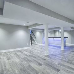 an empty living room with wood flooring and white columns in the center is lit by recessed lighting