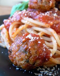 spaghetti with meatballs and sauce on a black plate