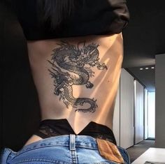 a woman's back with a dragon tattoo on her lower body and the bottom part of her stomach