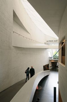 two people are walking up and down the stairs in an empty building with white walls