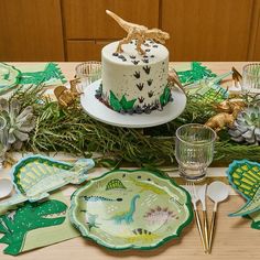 a table topped with plates and cake on top of a wooden table covered in plants