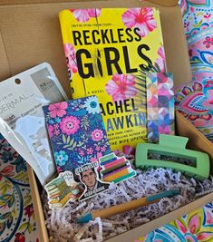 a box filled with books and other items on top of a bed covered in flowers